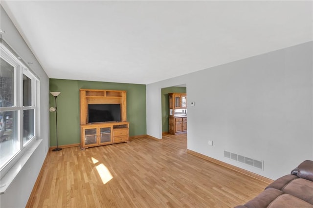 unfurnished living room featuring light wood-style floors, visible vents, and baseboards