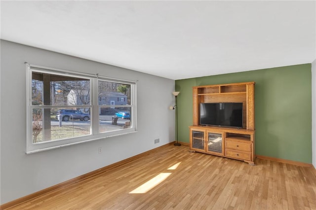 unfurnished living room with visible vents, baseboards, and wood finished floors