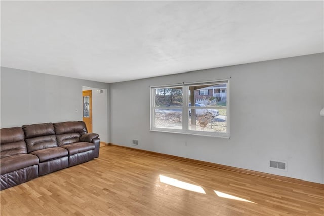 living area with baseboards, visible vents, and wood finished floors