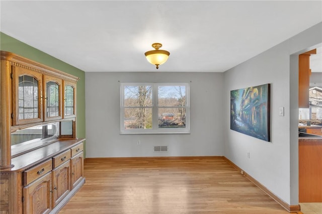 dining room featuring light wood-style flooring, visible vents, and baseboards