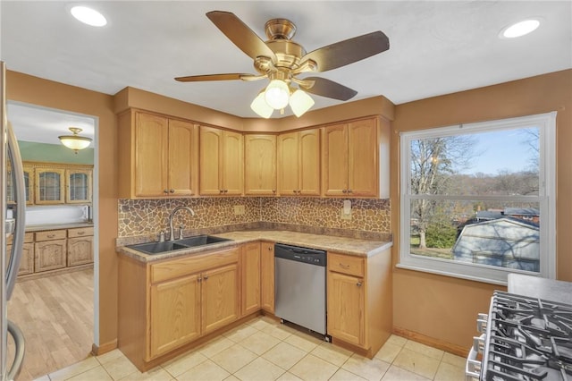 kitchen with light countertops, decorative backsplash, appliances with stainless steel finishes, light tile patterned flooring, and a sink