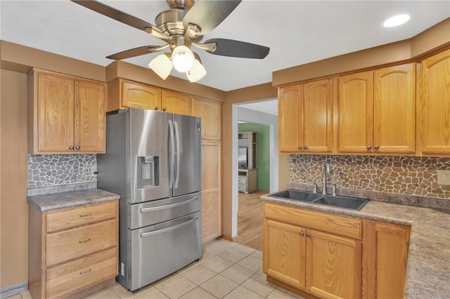 kitchen featuring stainless steel fridge, backsplash, a sink, and light tile patterned flooring