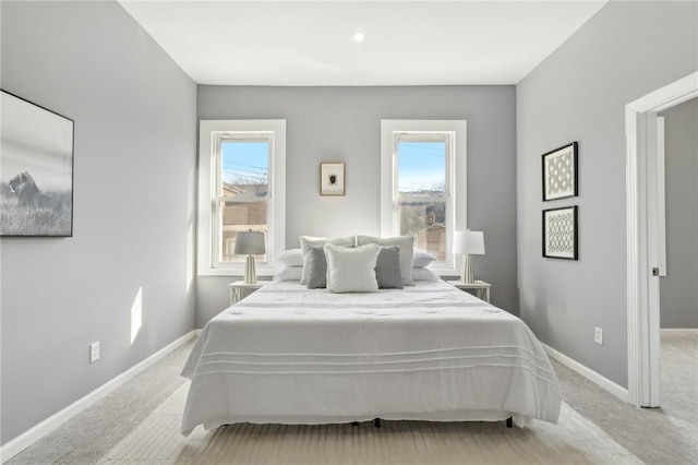 bedroom with multiple windows, baseboards, and light colored carpet