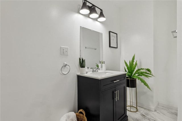 bathroom with marble finish floor, vanity, and baseboards