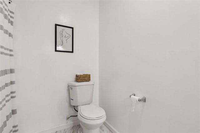 bathroom featuring a shower with shower curtain, toilet, and baseboards