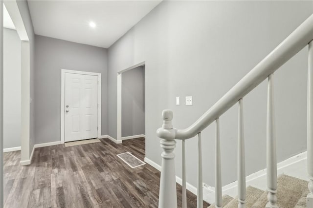 entrance foyer with baseboards, visible vents, stairway, and wood finished floors