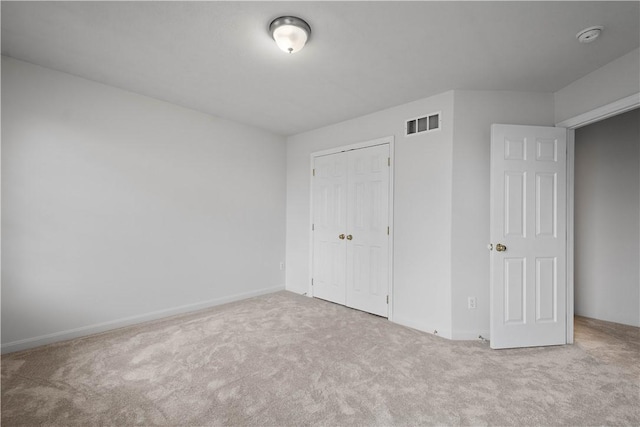 unfurnished bedroom with carpet, visible vents, and a closet