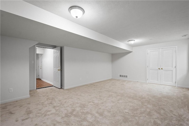 finished basement featuring carpet, a textured ceiling, visible vents, and baseboards