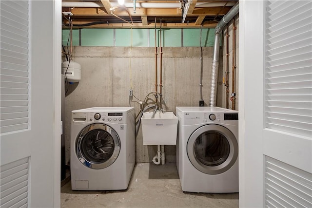 washroom featuring laundry area, washing machine and dryer, and a sink