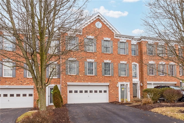 view of property featuring driveway, a garage, and brick siding