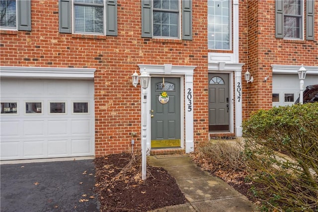 view of exterior entry featuring brick siding and an attached garage