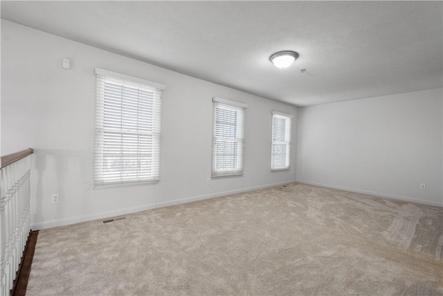 carpeted spare room featuring visible vents and baseboards