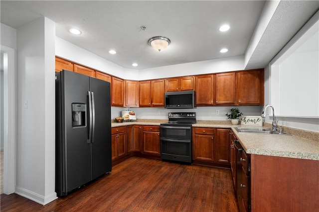 kitchen with range with two ovens, a sink, black fridge, brown cabinetry, and stainless steel microwave