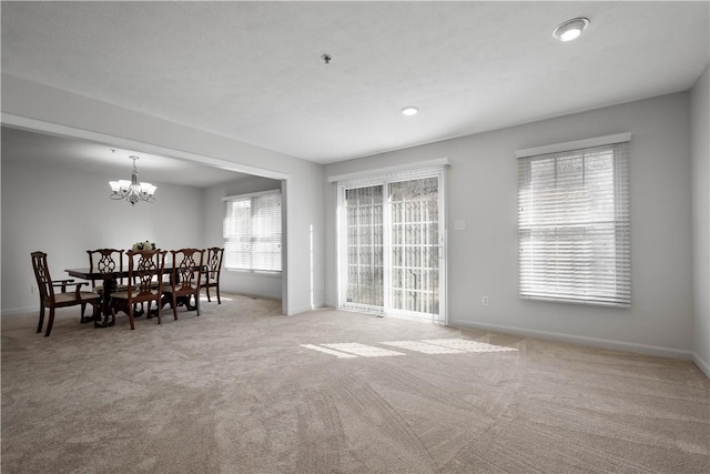 unfurnished dining area featuring carpet floors, a notable chandelier, and baseboards