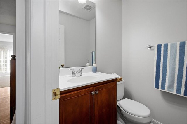 half bath featuring toilet, visible vents, and vanity