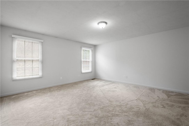 carpeted empty room featuring baseboards