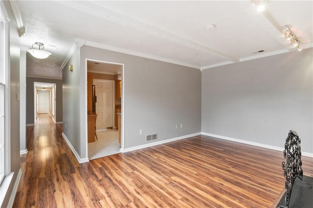 spare room featuring visible vents, baseboards, and wood finished floors