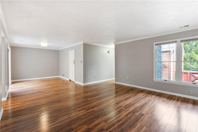 empty room featuring visible vents, ornamental molding, baseboards, and wood finished floors