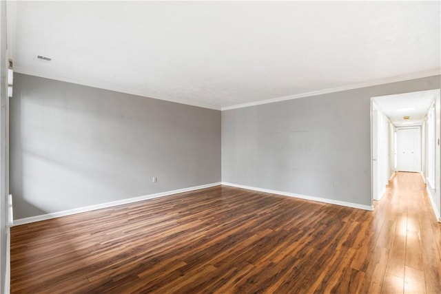 unfurnished room with visible vents, baseboards, wood finished floors, and ornamental molding