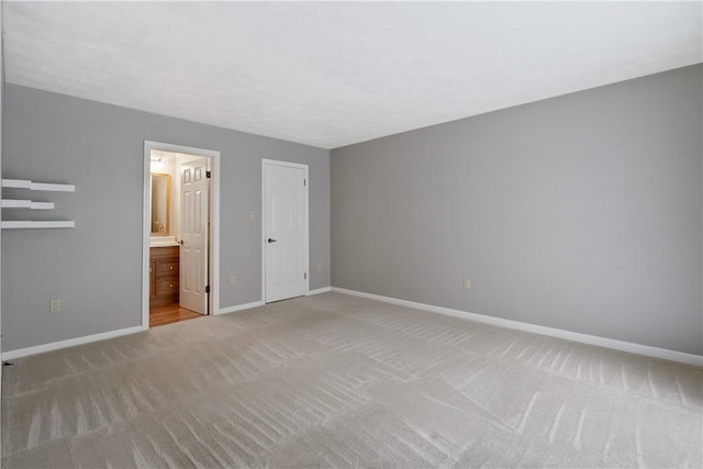 unfurnished bedroom with light colored carpet, baseboards, and connected bathroom