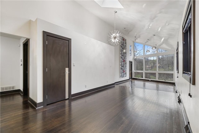 spare room with a skylight, wood finished floors, visible vents, and an inviting chandelier