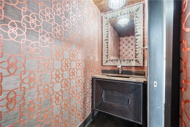 bathroom with wood finished floors, vanity, and an inviting chandelier