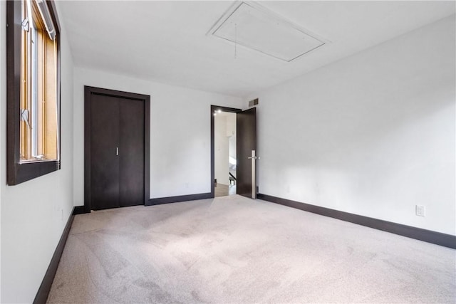 unfurnished bedroom featuring visible vents, carpet floors, attic access, and baseboards