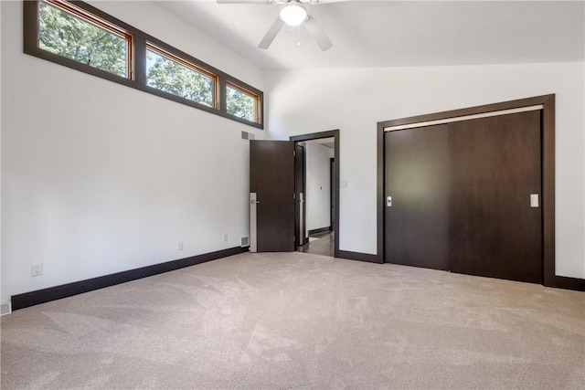 unfurnished bedroom featuring lofted ceiling, a closet, carpet, and baseboards