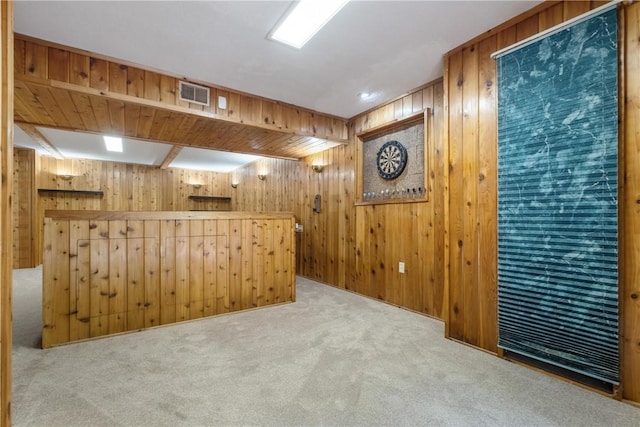 interior space with carpet floors, wooden walls, visible vents, and a dry bar