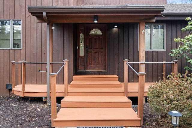 view of exterior entry featuring roof with shingles