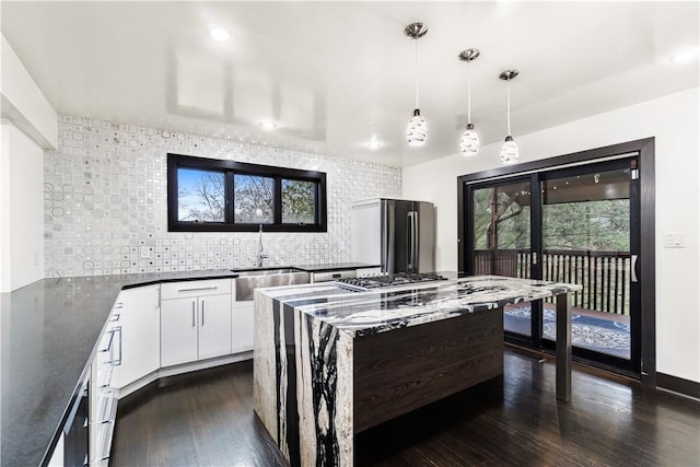 kitchen with decorative backsplash, dark countertops, appliances with stainless steel finishes, dark wood-style flooring, and a sink