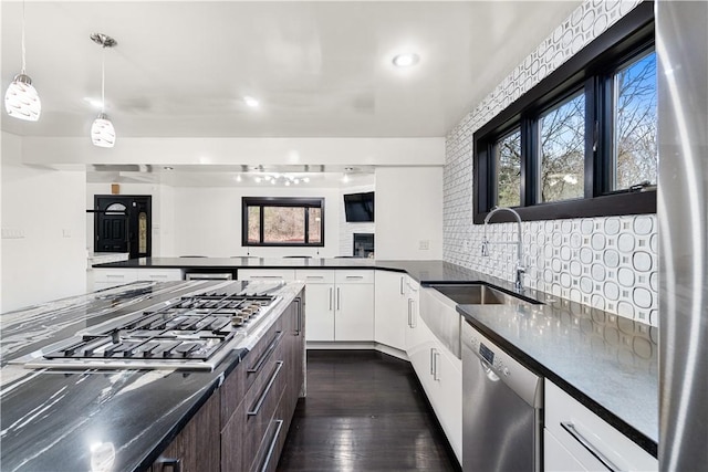 kitchen with plenty of natural light, stainless steel appliances, dark countertops, and a sink