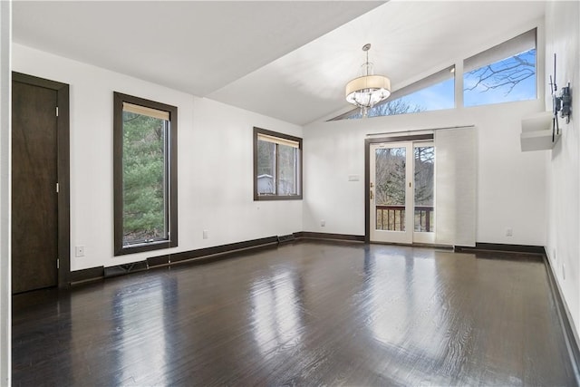 empty room with visible vents, baseboards, wood finished floors, vaulted ceiling, and a notable chandelier