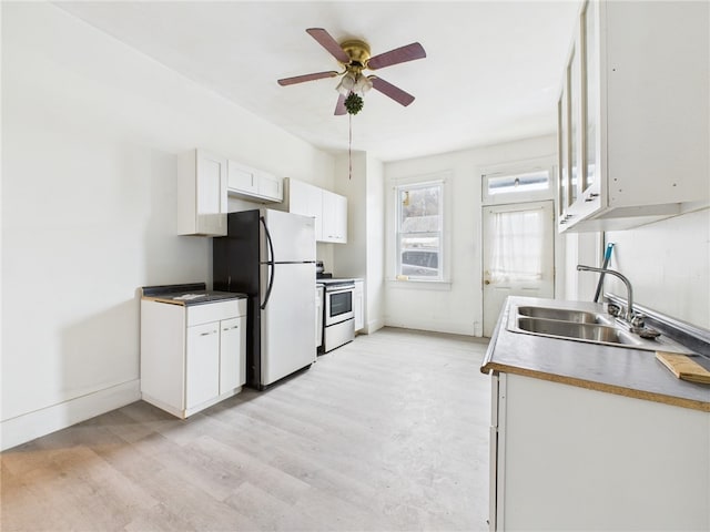 kitchen featuring light wood finished floors, freestanding refrigerator, stainless steel range with electric cooktop, white cabinets, and a sink