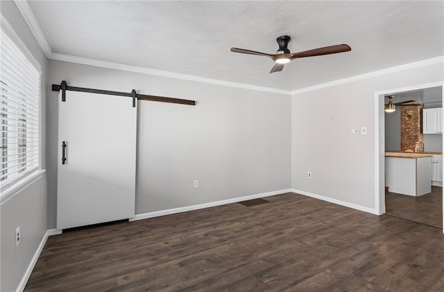 unfurnished bedroom with dark wood-type flooring, crown molding, baseboards, and a barn door