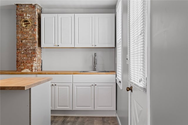 kitchen with white cabinets, a sink, wood counters, and wood finished floors