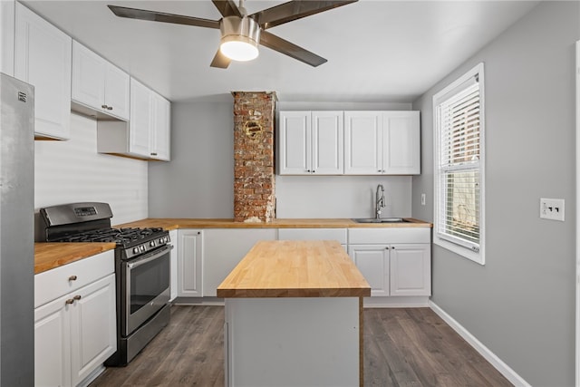 kitchen featuring dark wood-style floors, wood counters, appliances with stainless steel finishes, white cabinetry, and a sink