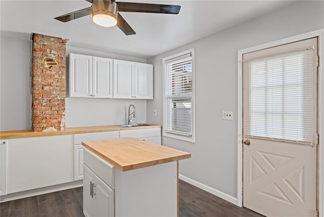 kitchen with wood counters, white cabinetry, dark wood-type flooring, and a sink