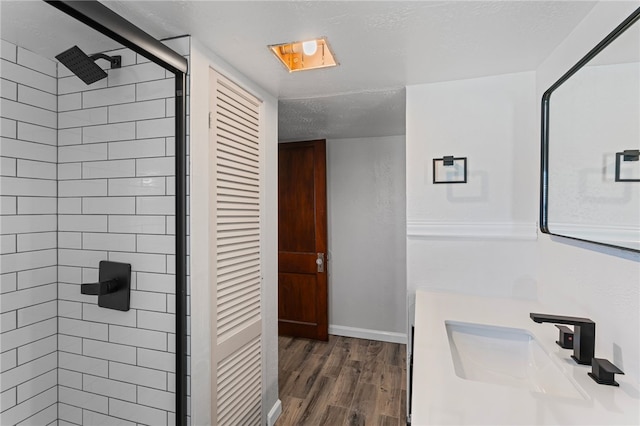 bathroom with a textured ceiling, wood finished floors, a sink, baseboards, and a shower stall