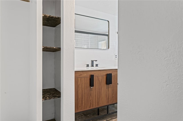 bathroom featuring a textured wall, vanity, and wood finished floors