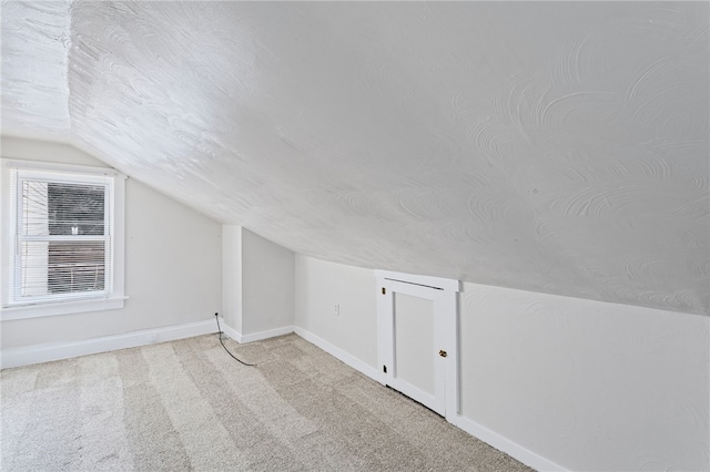 additional living space featuring carpet flooring, vaulted ceiling, a textured ceiling, and baseboards