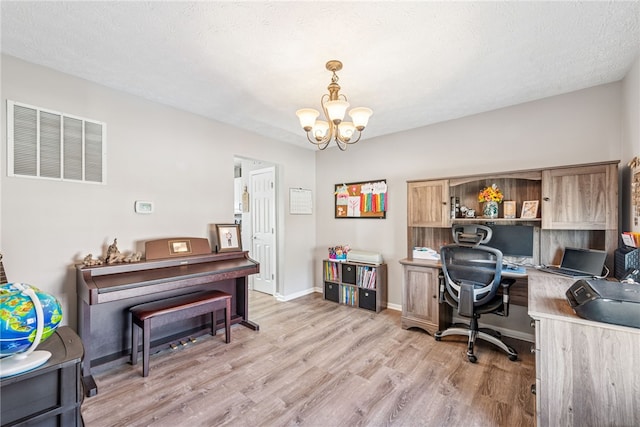 office area with a chandelier, a textured ceiling, light wood-style flooring, visible vents, and baseboards