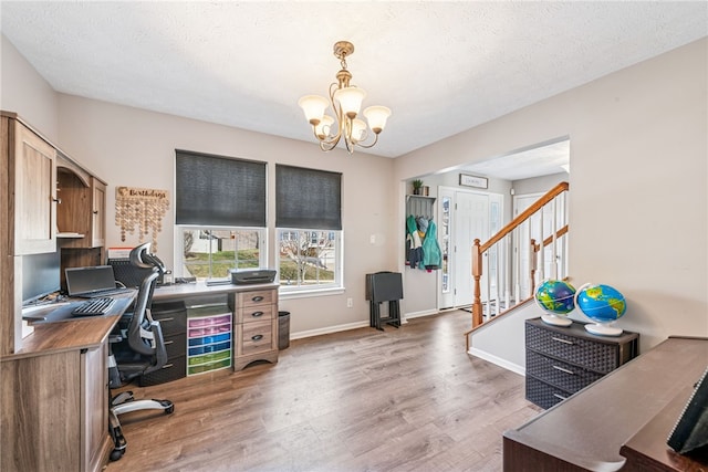 home office with a textured ceiling, light wood-type flooring, baseboards, and a notable chandelier