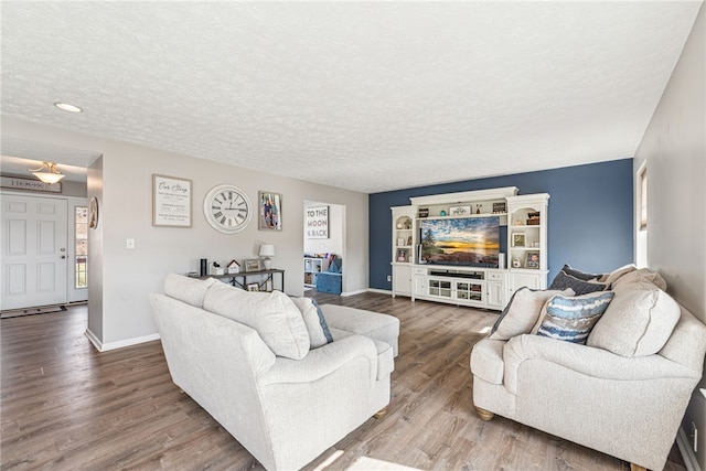 living area with a textured ceiling, baseboards, and wood finished floors