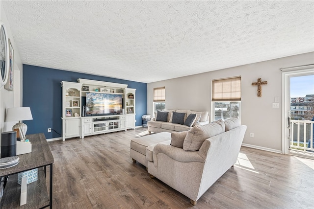 living area with a textured ceiling, baseboards, and wood finished floors