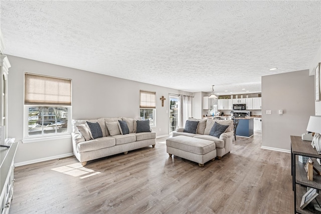 living room featuring a wealth of natural light, light wood-type flooring, and baseboards