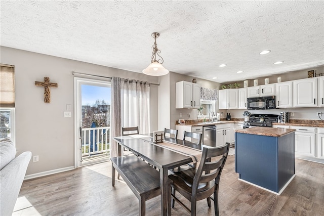 dining space featuring light wood-style flooring, baseboards, a textured ceiling, and recessed lighting