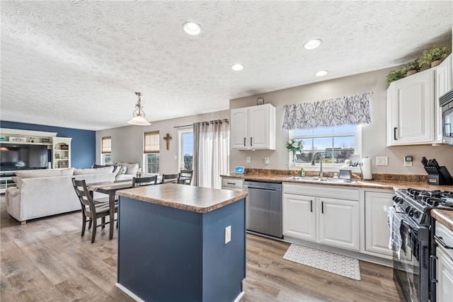 kitchen featuring a center island, stainless steel appliances, light wood-style floors, white cabinetry, and a sink