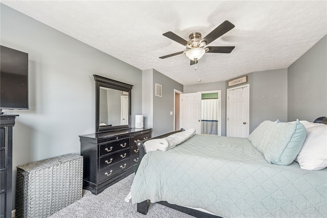 bedroom featuring light carpet, a textured ceiling, visible vents, and a ceiling fan