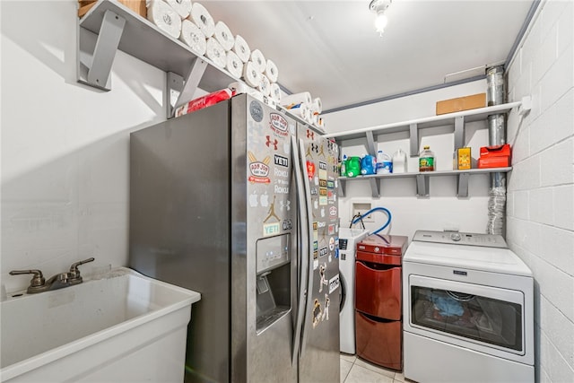 kitchen with concrete block wall, stainless steel refrigerator with ice dispenser, washing machine and clothes dryer, open shelves, and a sink